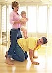 Man on all fours, woman holding baby on his back