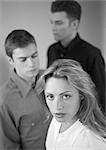 Woman standing in front of two men, portrait, b&w