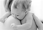 Mother holding infant on bare shoulder, b&w