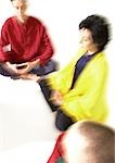 Group of people sitting on floor indian style, meditating, blurred