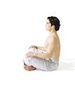 Topless man sitting on floor indian style, meditating, side view
