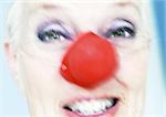 Mature woman wearing clown nose, close-up, blurred