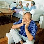 Mature man sitting on floor, three women in background on couch