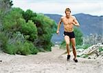 Man in shorts running along Mountain trail.