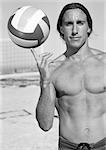 Young bare-chested man, holding volleyball on finger, portait, b&w.