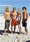 Quatre jeunes gens sur la plage avec volleyball, souriant à la caméra.