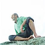 Mature man sitting on rocks, low angle view