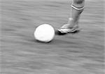 Foot of player and soccer ball, blurred, b&w.