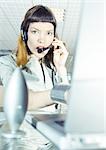 Woman wearing headset, using computer, portrait