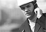 Man with hard hat using cell phone, close-up, b&w