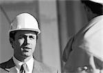 Man in suit wearing hard hat, close-up, b&w