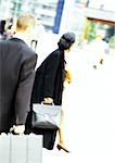 Businessman and businesswoman holding briefcases, rear view, blurred