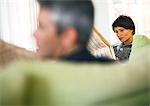 Businessman and businesswoman reading newspaper, blurred foreground