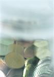 Variety of coins mixed together in plastic container, close-up