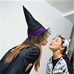 Two girls wearing costumes, sticking out tongues at each other