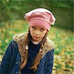Girl outside wearing pink beret, winter coat, pouting, looking at camera