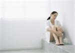 Woman sitting in corner with knees up, blurred