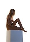 Nackte Frau sitzend mit Knie bis auf Sockel, Seitenansicht