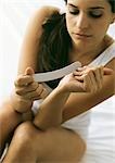 Woman filing nails on bed