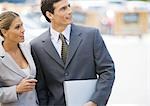 Businesswoman and man standing close together, looking up