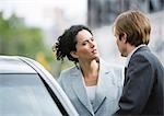 Businesswoman and man speaking next to car