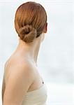 Woman with red hair in bun and strapless top, rear view