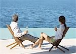 Couple assis avec verres de champagne, avec vue sur l'eau