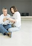 Mature couple sitting on floor looking at cds