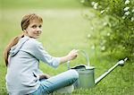 Girl sitting on grass with watering can