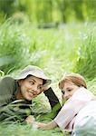 Young woman and girl lying in grass together