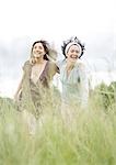 Two young female friends walking through grass