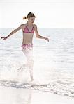 Girl running through surf on beach