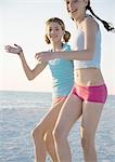 Two preteen girls running on beach