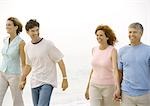 Two mature couples walking on beach