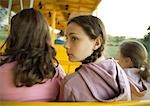 Preteen girls riding train in amusement park, rear view
