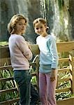 Two girls leaning against wooden fence