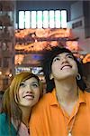 Teenage couple looking up, lights in background
