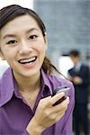 Young woman holding cell phone, laughing