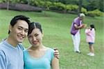 Couple smiling at camera, senior woman and girl in background