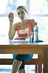 Young woman in exercise clothing having snack in health club cafeteria