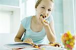 Girl eating junk food while doing homework