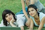 Group of young friends lying on grass using laptop