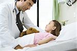 Doctor talking with girl lying in hospital bed