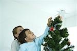 Boy and mother decorating Christmas tree