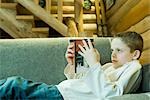 Boy reclining on couch, reading book