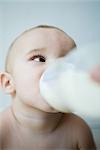 Baby drinking milk from bottle, head and shoulders, selective focus