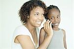 Mère et fille ensemble à l'aide de téléphone portable, souriant