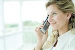 Woman using cell phone, smiling, looking up