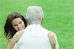 Teenage girl hugging her grandfather outdoors, smiling