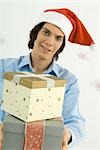 Young man holding Christmas gifts toward camera, smiling